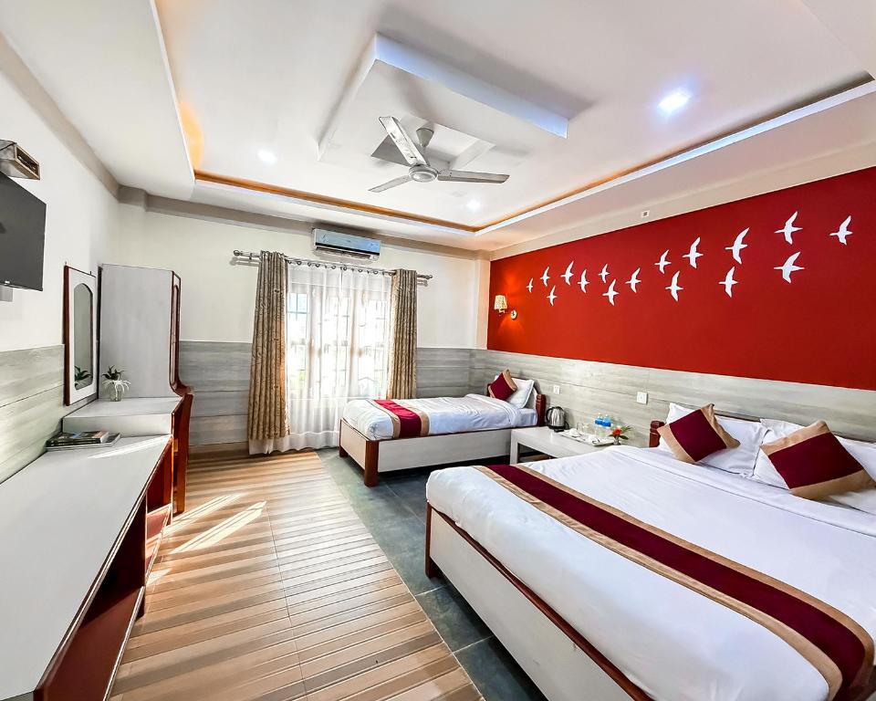 a hotel room with two beds and a red wall at Chitwan Forest Resort with swimming pool , Chitwan National Park in Sauraha
