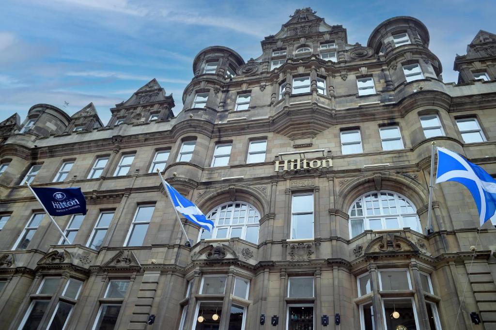a building with flags in front of it at Hilton Edinburgh Carlton in Edinburgh
