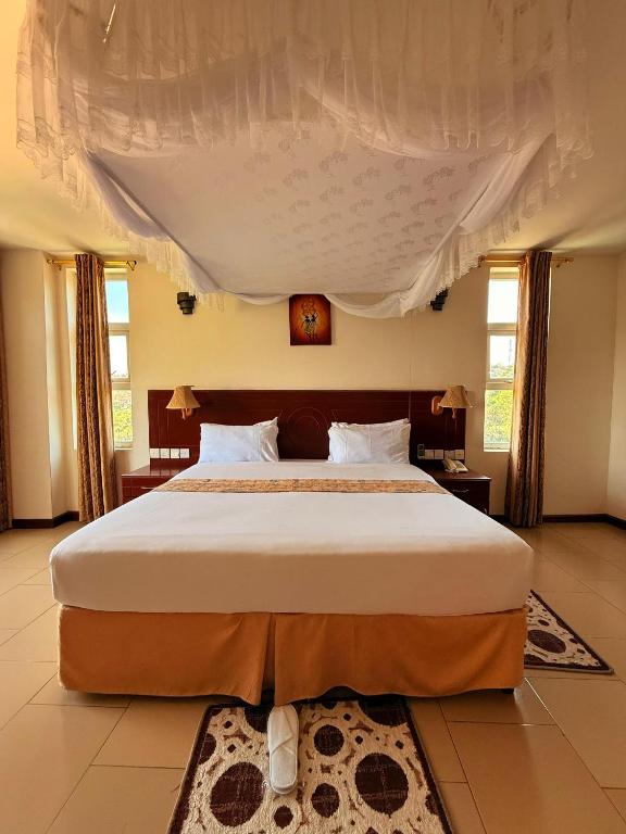 a bedroom with a large bed with a canopy at Isamilo Grand Hotel in Mwanza