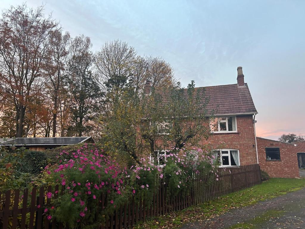 a brick house with a fence and flowers at Church Farm, Legbourne Louth in Legbourne