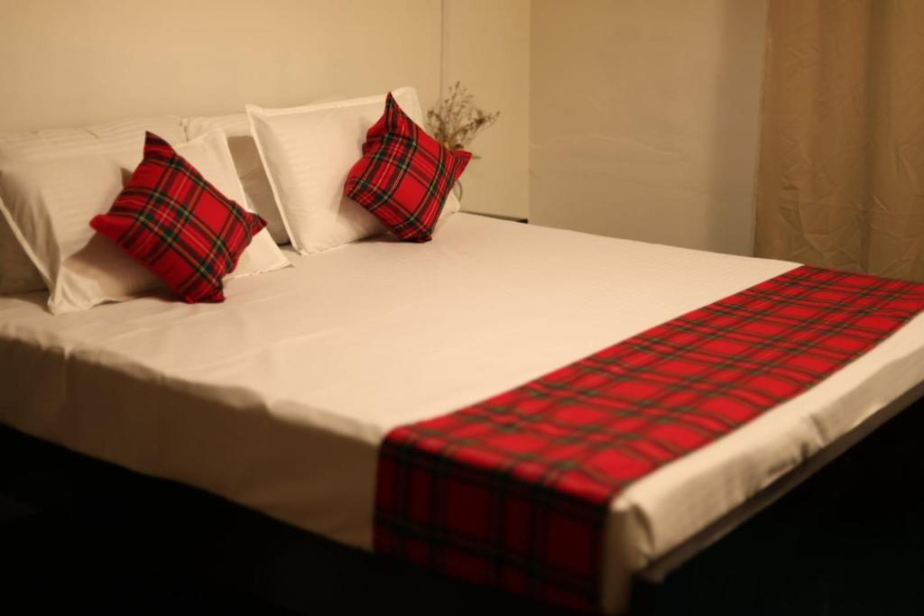 a bed with red and black plaid pillows on it at Meis cottage Umpling in Shillong
