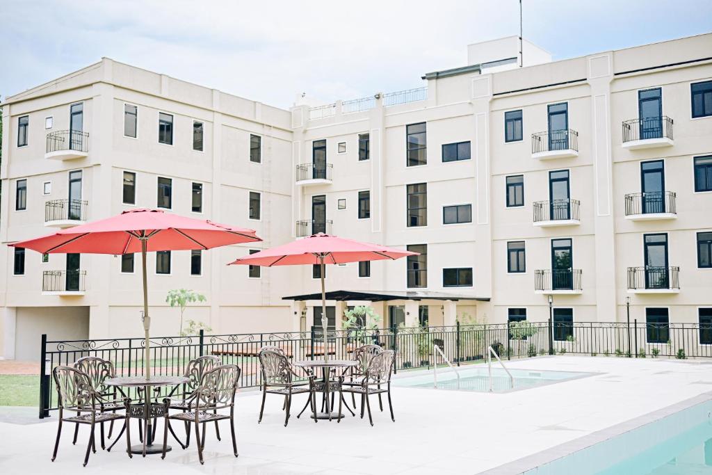 a patio with tables and umbrellas in front of a building at The Ancestry Suites in Wasig