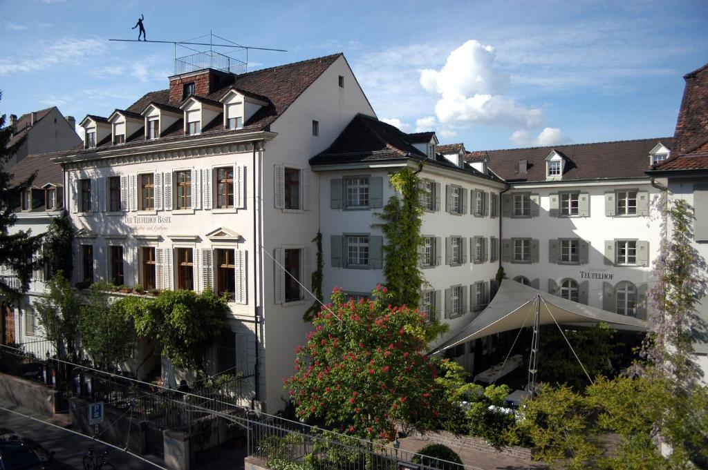 un grand bâtiment blanc avec un oiseau volant au-dessus dans l'établissement Gast - und Kulturhaus Der Teufelhof Basel, à Bâle