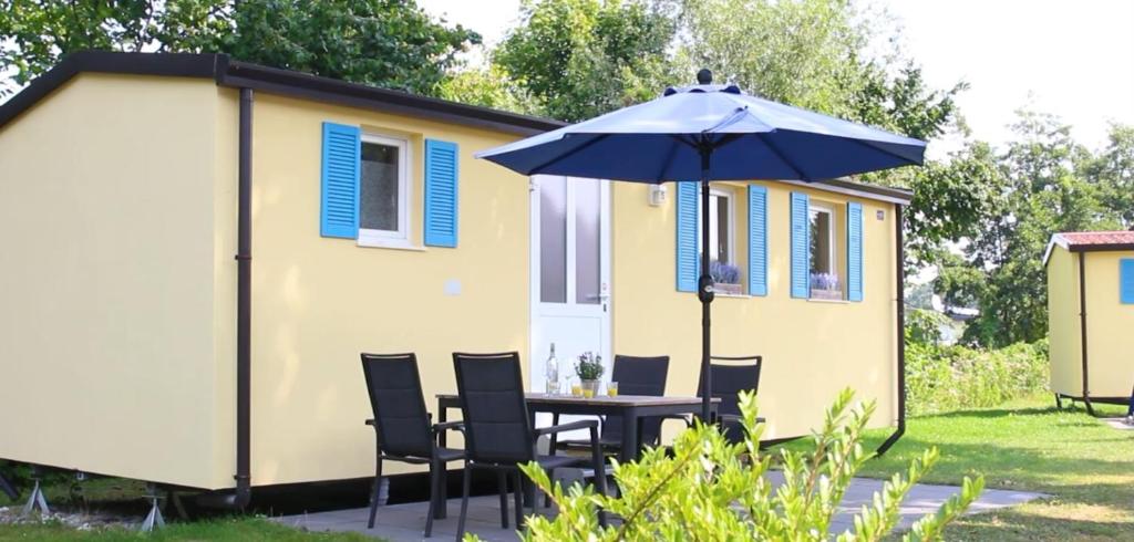 a table and chairs with an umbrella in front of a tiny house at Tiny House - Camping am Lippesee in Paderborn