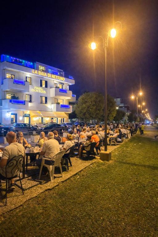 a group of people sitting at tables in front of a building at LA BAIA DI NETTUNO Il Gatto e La Volpe in Venetico