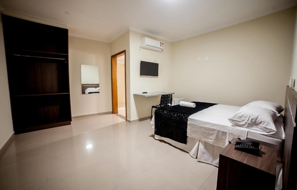 a bedroom with a bed and a desk in it at Apoema Hotel in Cuiabá