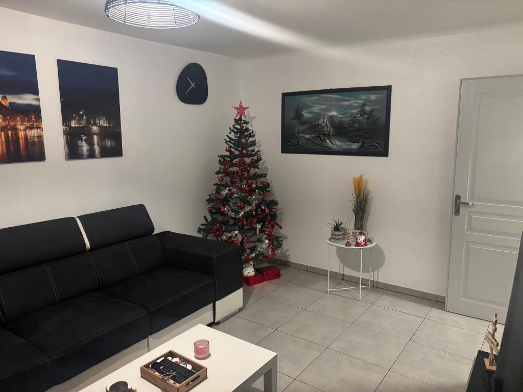 a living room with a christmas tree and a black couch at Maison chaleureuse Calme et tranquillité assurés Parking privé in Geispolsheim