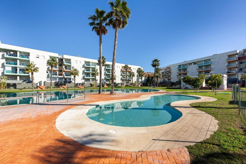 a swimming pool with palm trees in front of a building at Rincon de Almerimar Palm Beach Golf in Almerimar
