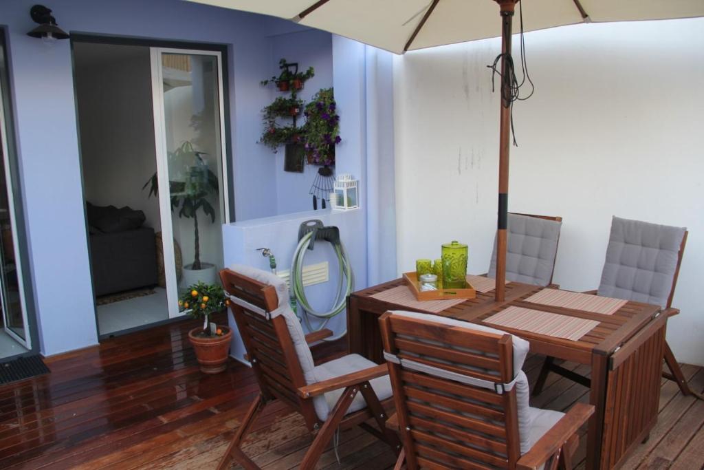 ein Esszimmer mit einem Tisch, Stühlen und einem Sonnenschirm in der Unterkunft Garden Apartment in Lissabon