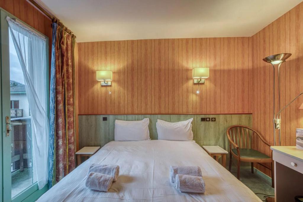a bedroom with a white bed with a window at Brit Hotel Florimont in Saint-Ferréol