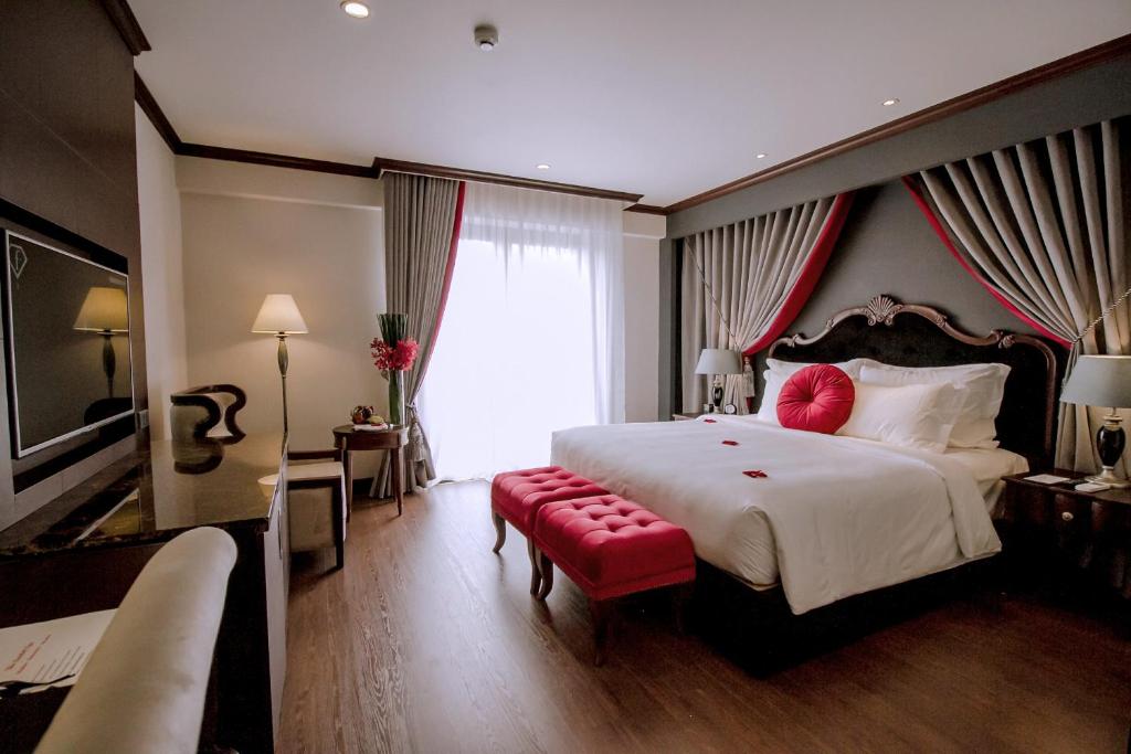 ein großes Schlafzimmer mit einem großen Bett und einer roten Bank in der Unterkunft The Scarlett Boutique Hotel in Hue