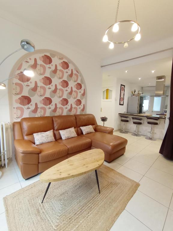 a living room with a brown leather couch and a table at Au Moulin d'Or in Lille