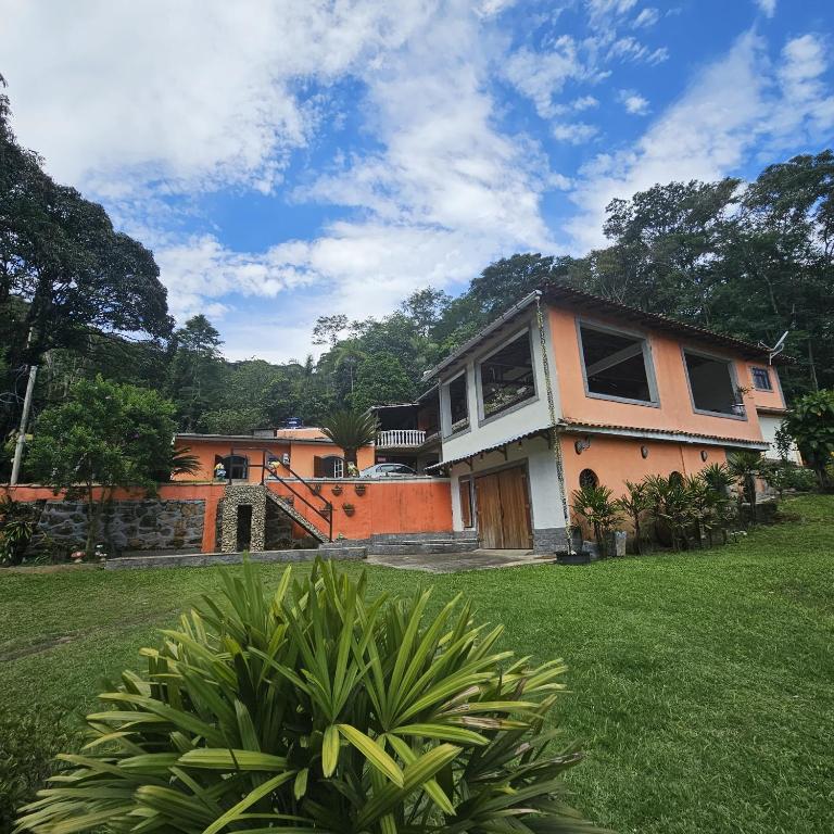 a house in a yard with a green lawn at Casa tia Rosa, hospedagem familiar Guapimirim RJ in Guapimirim
