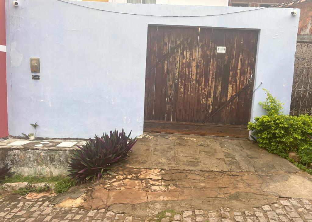 a garage with a wooden door on a white wall at Casa da May in Lençóis