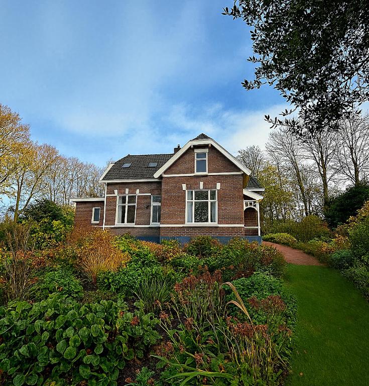 a brown brick house with a landscaped yard at Groepsverblijf Villa d'Uylenburgh in Hommerts
