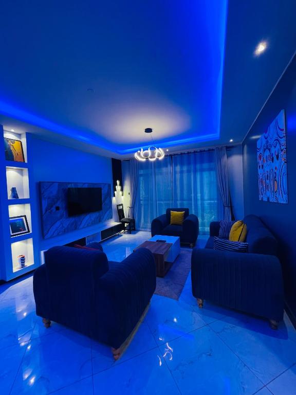 a blue living room with couches and a tv at Luxury homes ug in Kampala