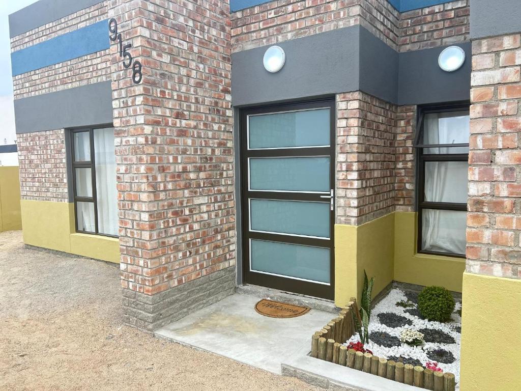 a brick building with a black door and windows at Pwake Luna Guesthouse in Swakopmund