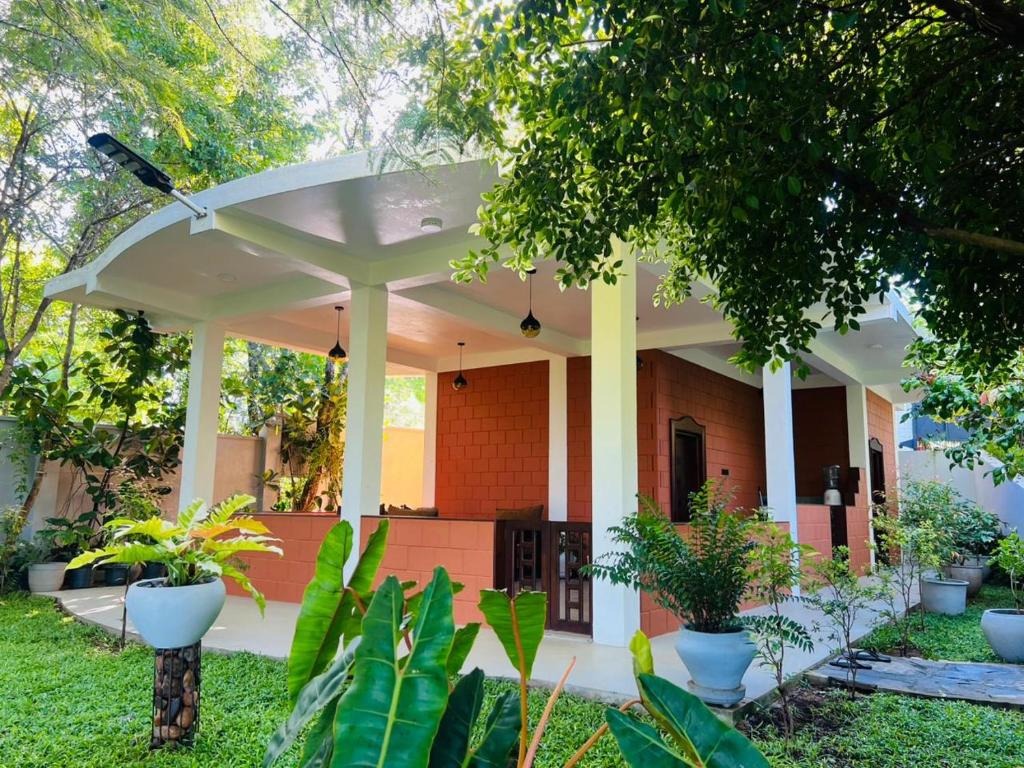 a white pergola in a yard with plants at Nature's Edge Udawalawa in Sinuggala