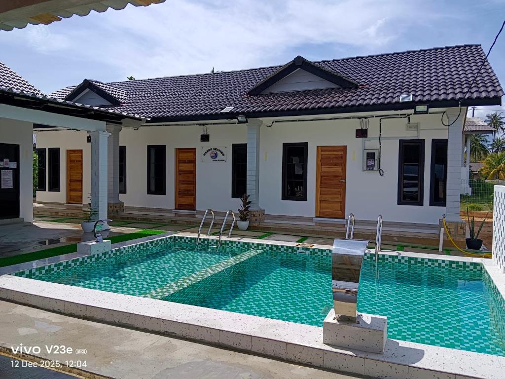 a swimming pool in front of a house at Makok Seaview roomstay in Kampung Penarik