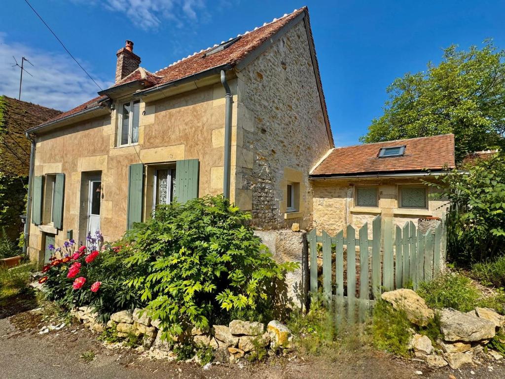 an old stone house with a fence and flowers at Sweet Pea Cottage in Donzy