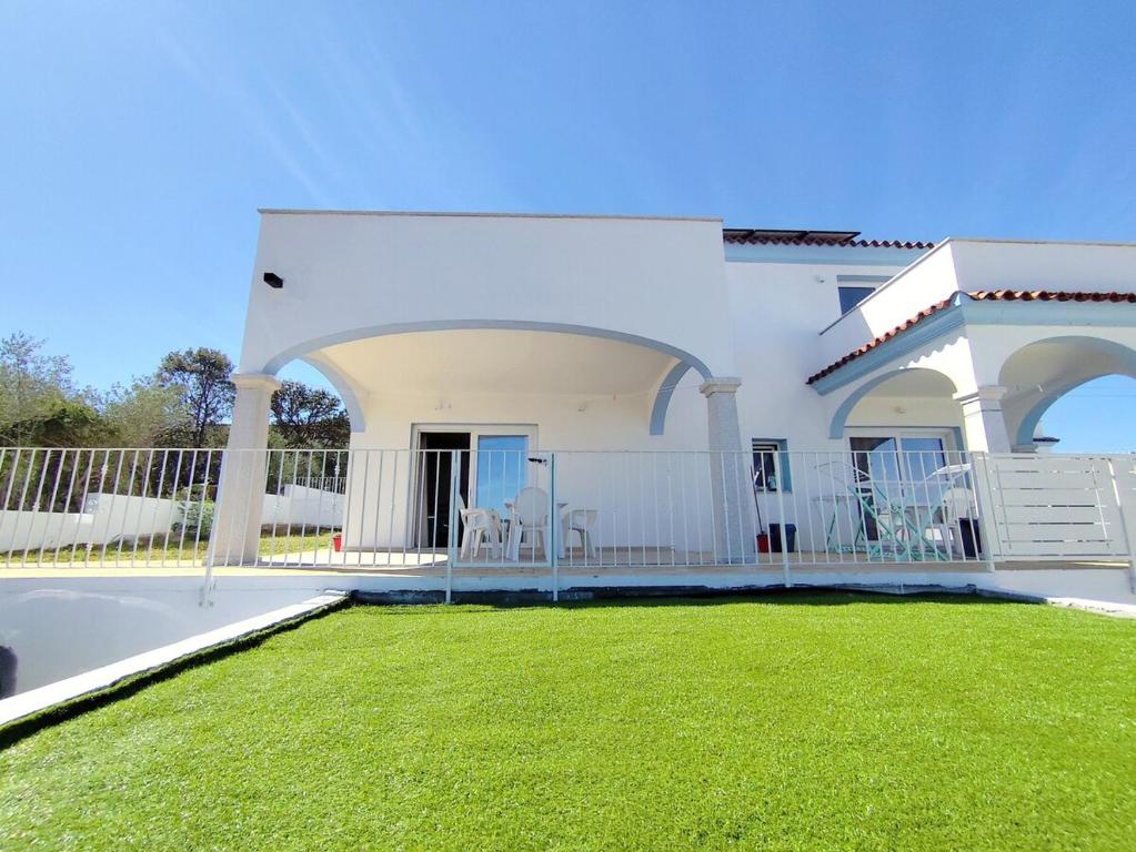 a white house with a lawn in front of it at Villetta Borgo Bianco 1 con piscina in condivisione in Budoni