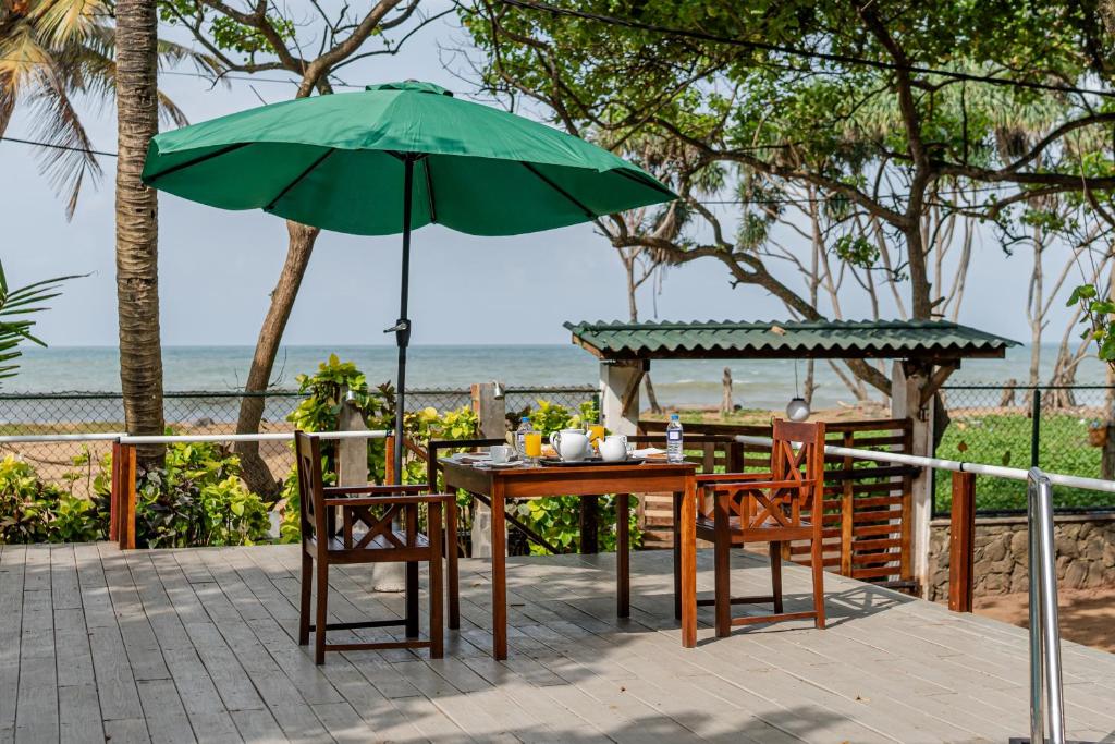 a table and chairs with a green umbrella at Lohas Beach Villa in Kalutara