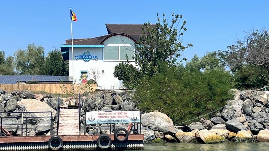 a boat in the water in front of a building at Casa de Vacanta Nufarul Crisan in Tulcea