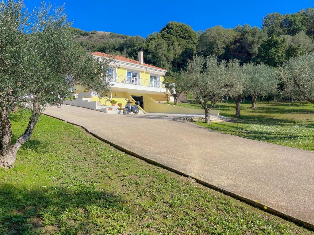 a yellow house with people sitting in front of it at Villa M&M met eigen zwembad in Kalamaki