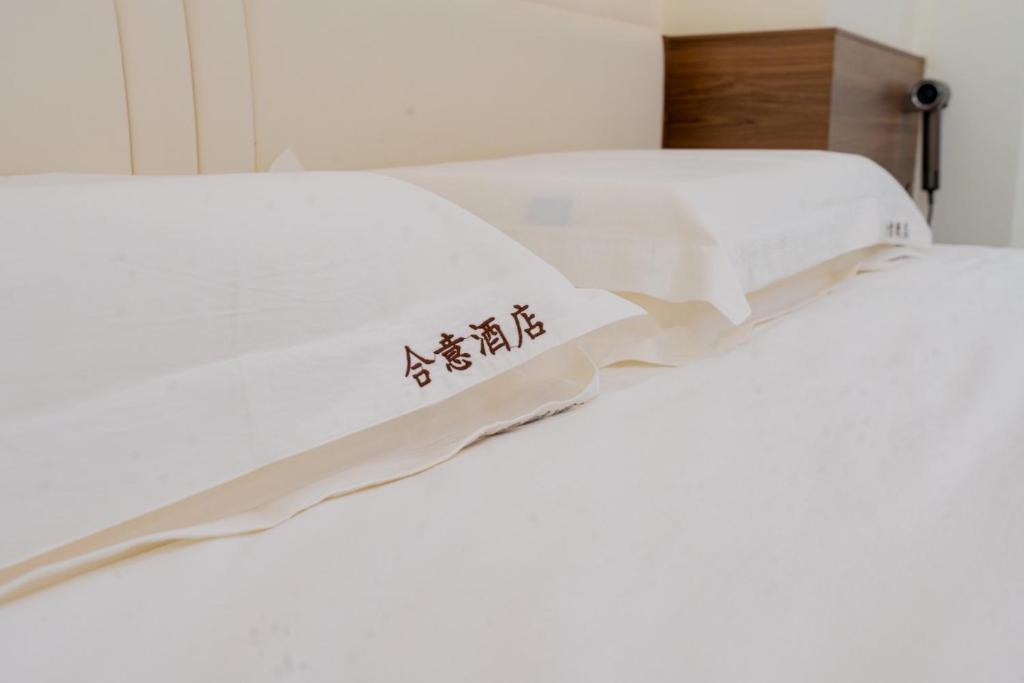 two beds with white sheets with asian writing on them at 合意酒店 in Việt Yên