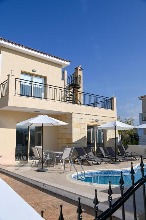 a house with a swimming pool with chairs and umbrellas at Sorelia Latchi Villas 2 - Merope Irena in Polis Chrysochous