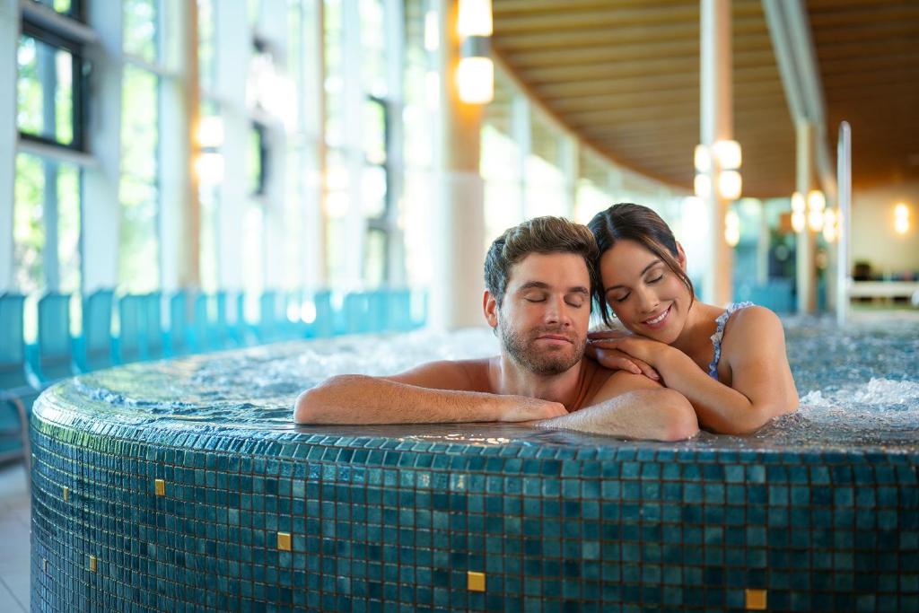 a man and woman laying in a swimming pool at Hotel Sole Felsen Welt in Gmünd