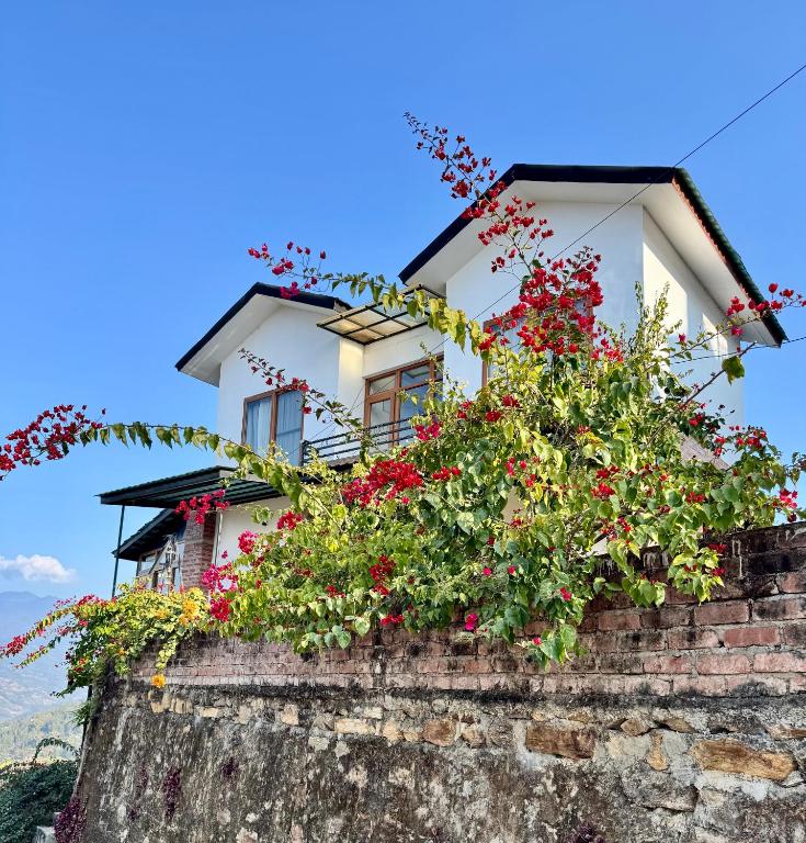 a house on top of a stone wall with flowers at Bagaan Villa Homestay in Ilām