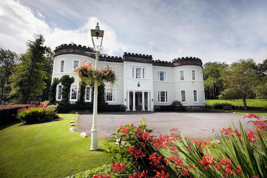 a large white house with a yard with flowers at Overwater Hall in Bassenthwaite