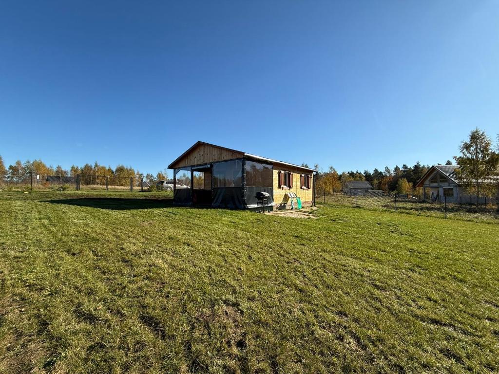 a house in a field with a grass field at Domki letniskowe Ruś in Ruś