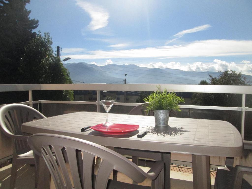 a table with a glass of wine on a balcony at Appartement Style Campagne - Vue montagne - Exposé plein Sud - Belle terrasse - in Font-Romeu