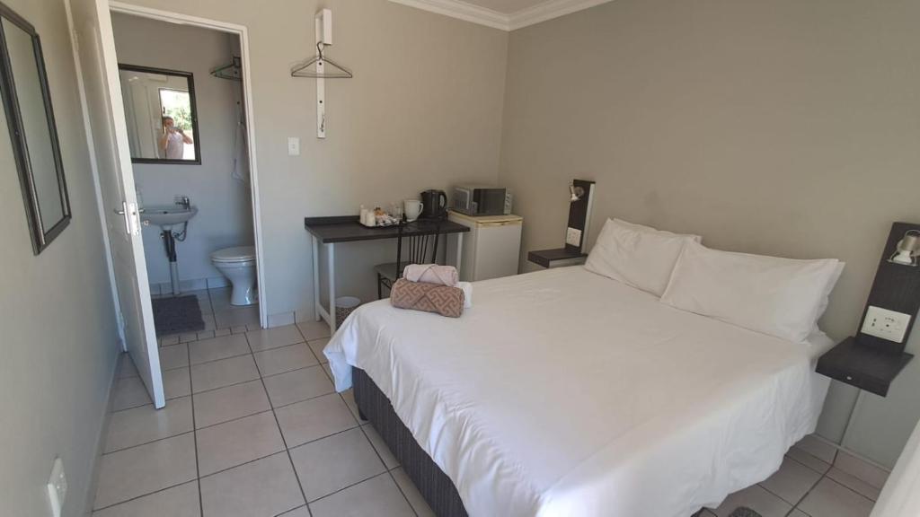 a bedroom with a white bed and a bathroom at Chrisserus Guest Rooms in Bloemfontein
