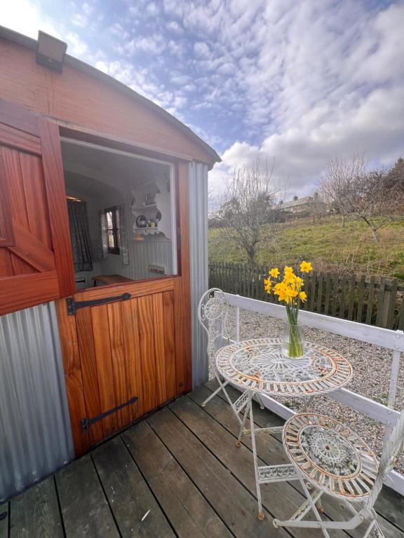 a patio with a table and chairs on a deck at Orchard Shepherds Hut in Calstock