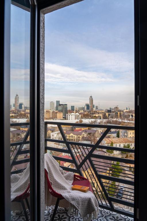 a balcony with two chairs and a view of a city at Blueloft 65 I Apartment with Balcony and City View in Tashkent