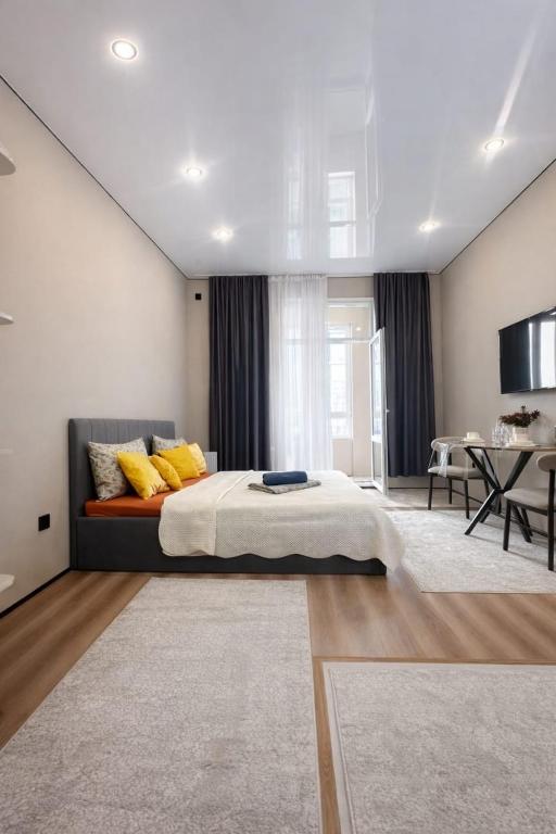 a bedroom with a large bed and a dining room at Современный апартамент Tandau в центре in Almaty