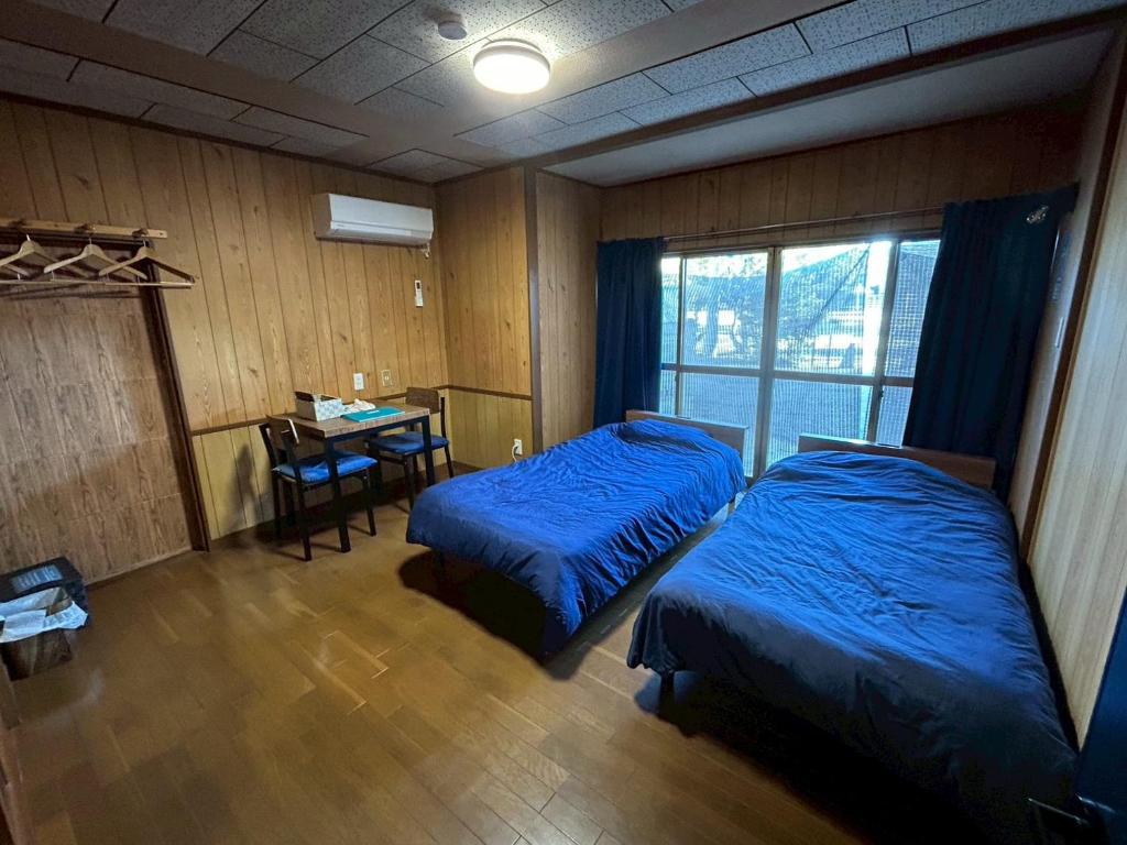a bedroom with two beds and a desk and a table at Denim-yado Ken-健- in Tamano