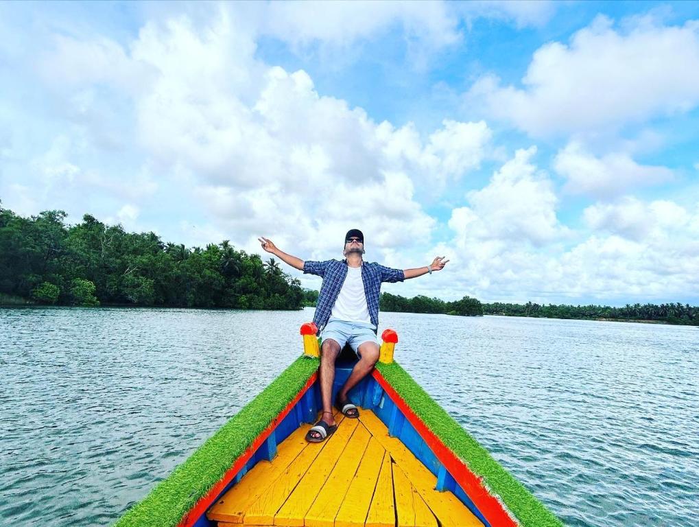 a man is sitting on a boat on the water at Eden homes in Honāvar