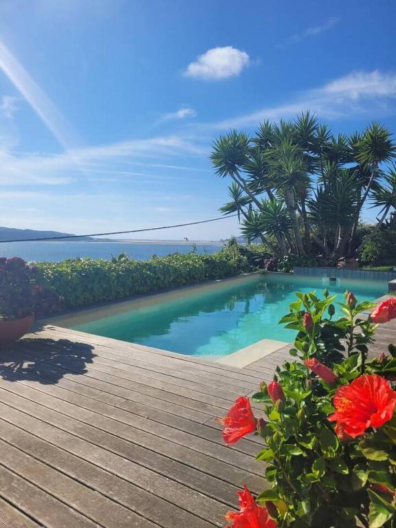 a wooden deck with a swimming pool and flowers at Óbidos Lagoon Refuge in Foz do Arelho