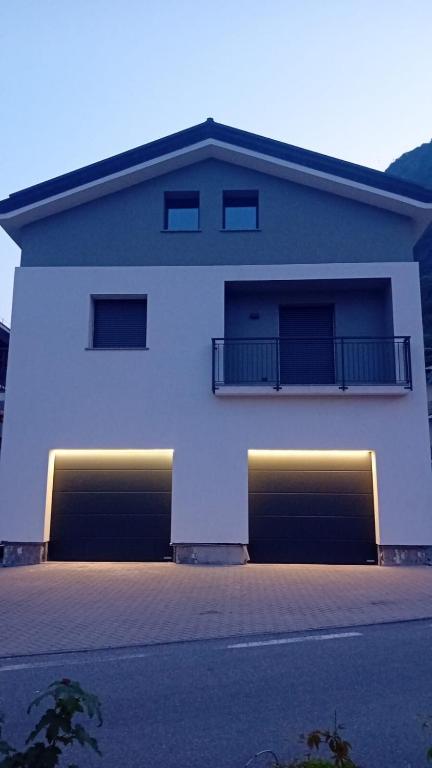 a white building with two garages in front of it at Beato Mario Apartments in Tirano
