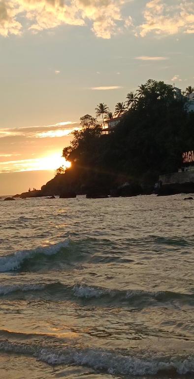 an island in the ocean with the sunset in the background at Luiza Guest House in Baga