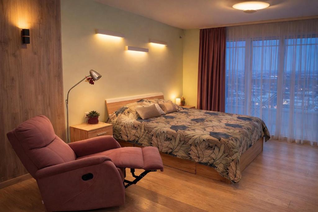a bedroom with a bed and a chair and a window at Comfy Retreat on Kotsubinsky street in Vinnytsya