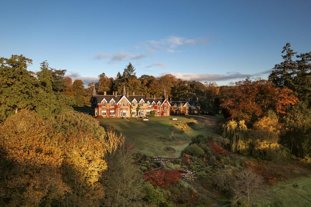 a large house on a golf course with trees at Ballathie House Hotel in Perth