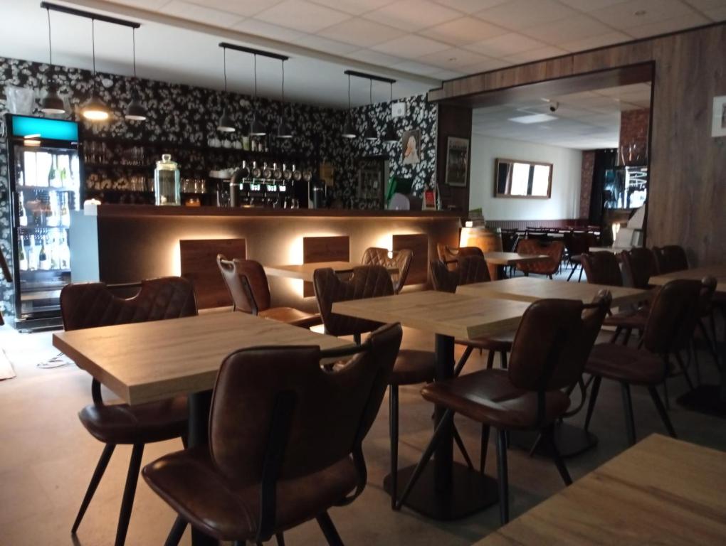 a restaurant with wooden tables and chairs and a bar at Hôtel de l'abbaye in Saint-Savin