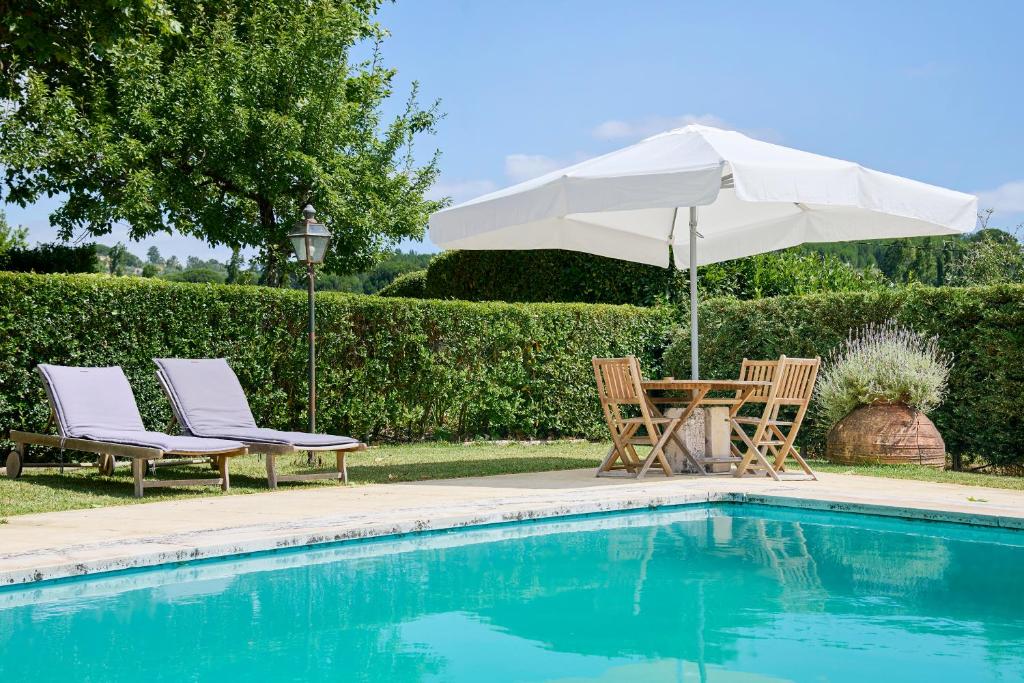 a table and chairs with an umbrella next to a pool at Quinta da Alcaidaria Mor in Ourém