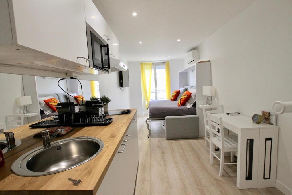 a kitchen with a sink and a room with a bed at Rempart du Chateau-SV82 StudioVincennes in Vincennes