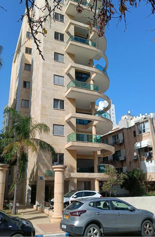 a tall building with cars parked in front of it at sitbonim in Netanya